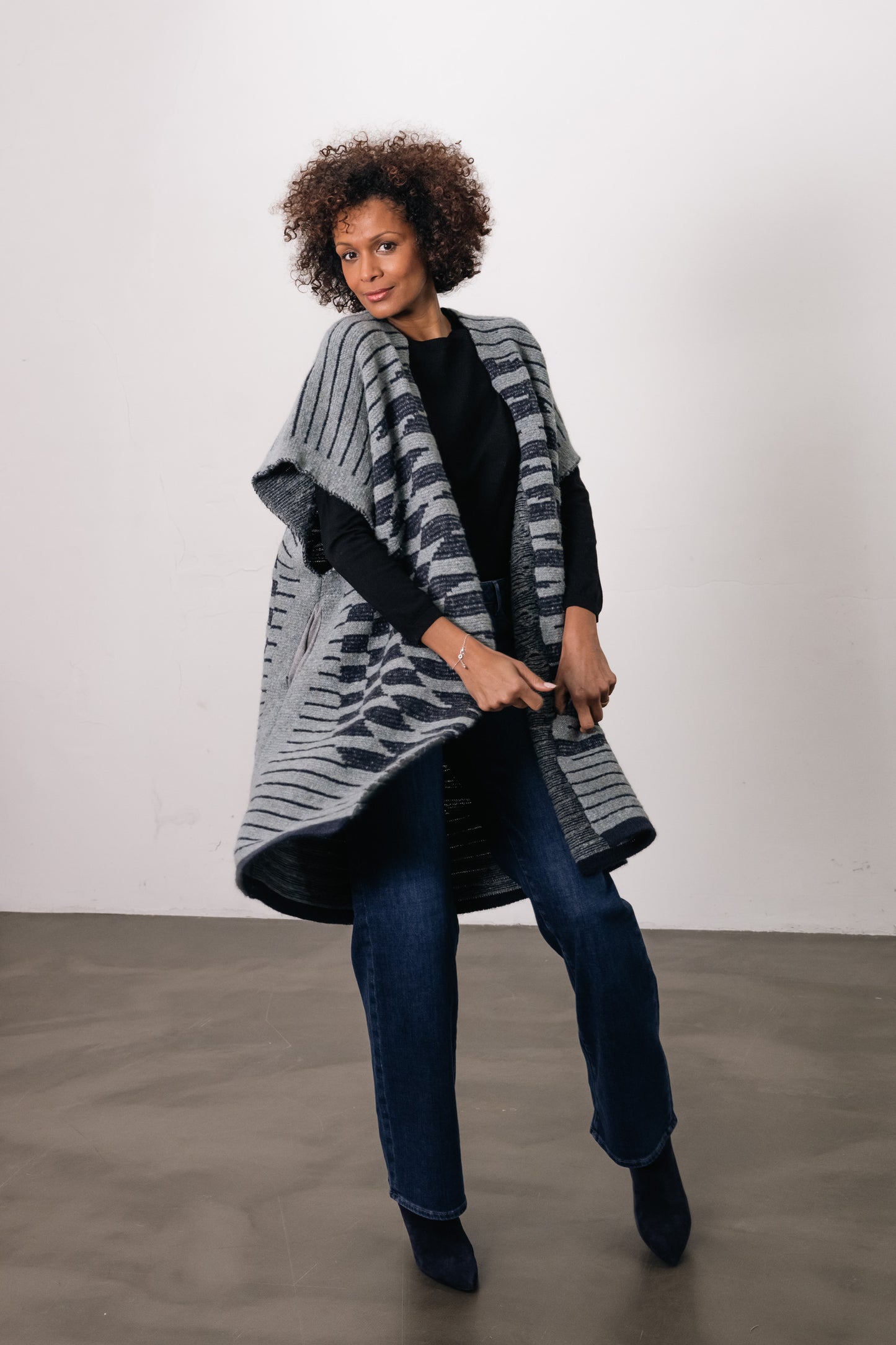 woman wears gray/blue vest with circle on back