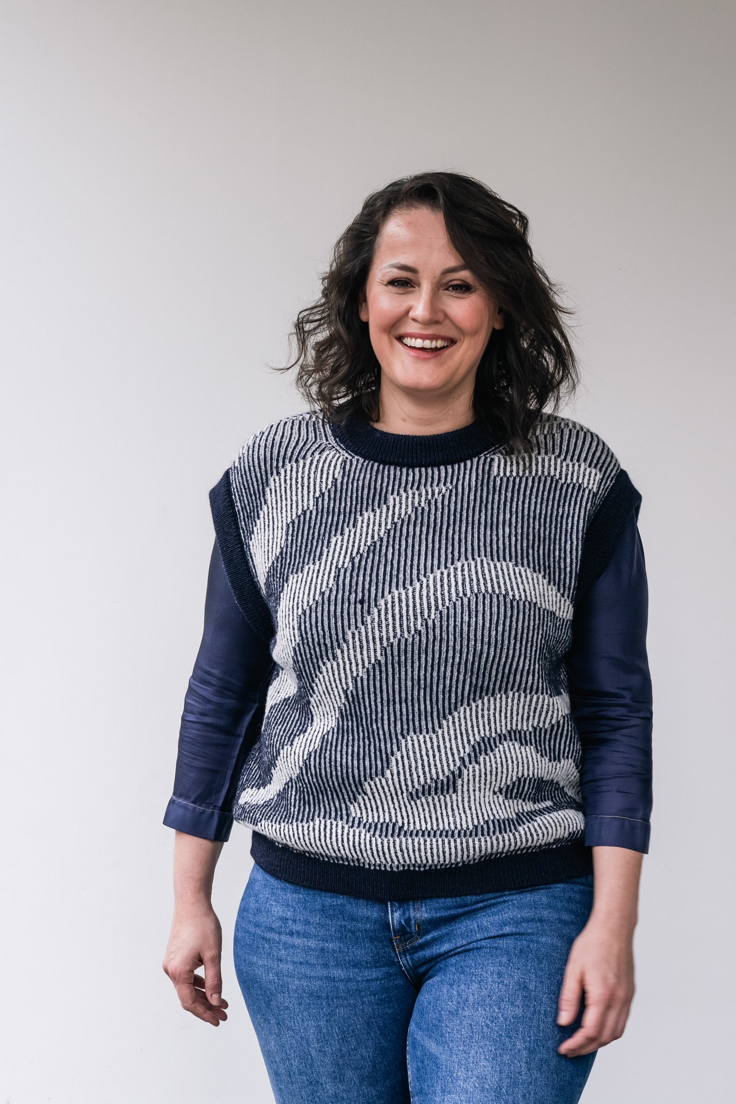 women wears a wollen dark blue-white debardeur and underneath a silk dark blue blouse