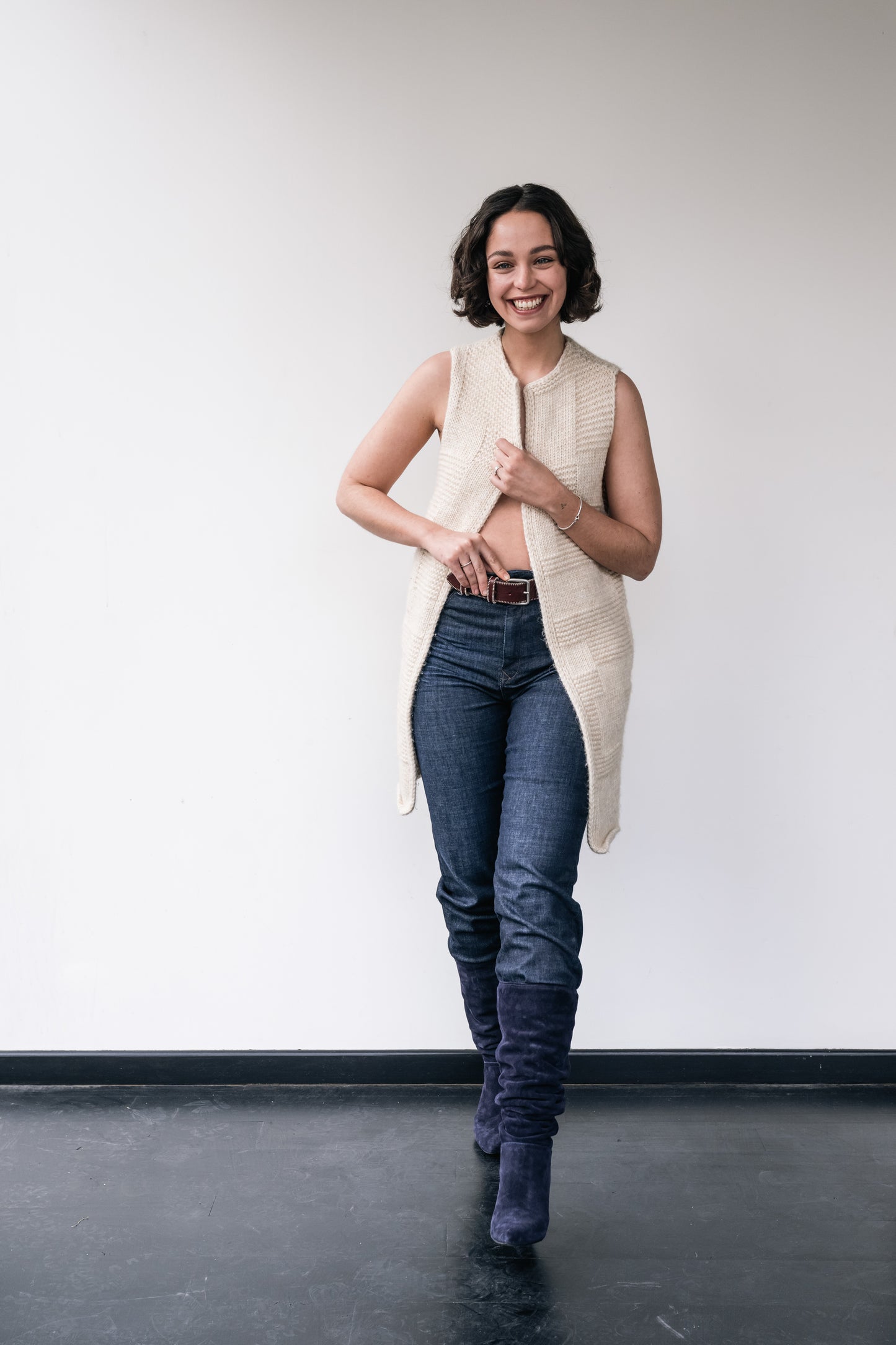 woman wears a white long wool cardigan and underneath a leather bordeaux belt with stitchings