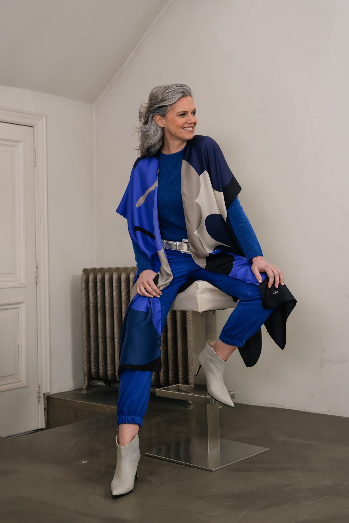 woman sitting on stool wearing silk long kimono with blue large flowers.