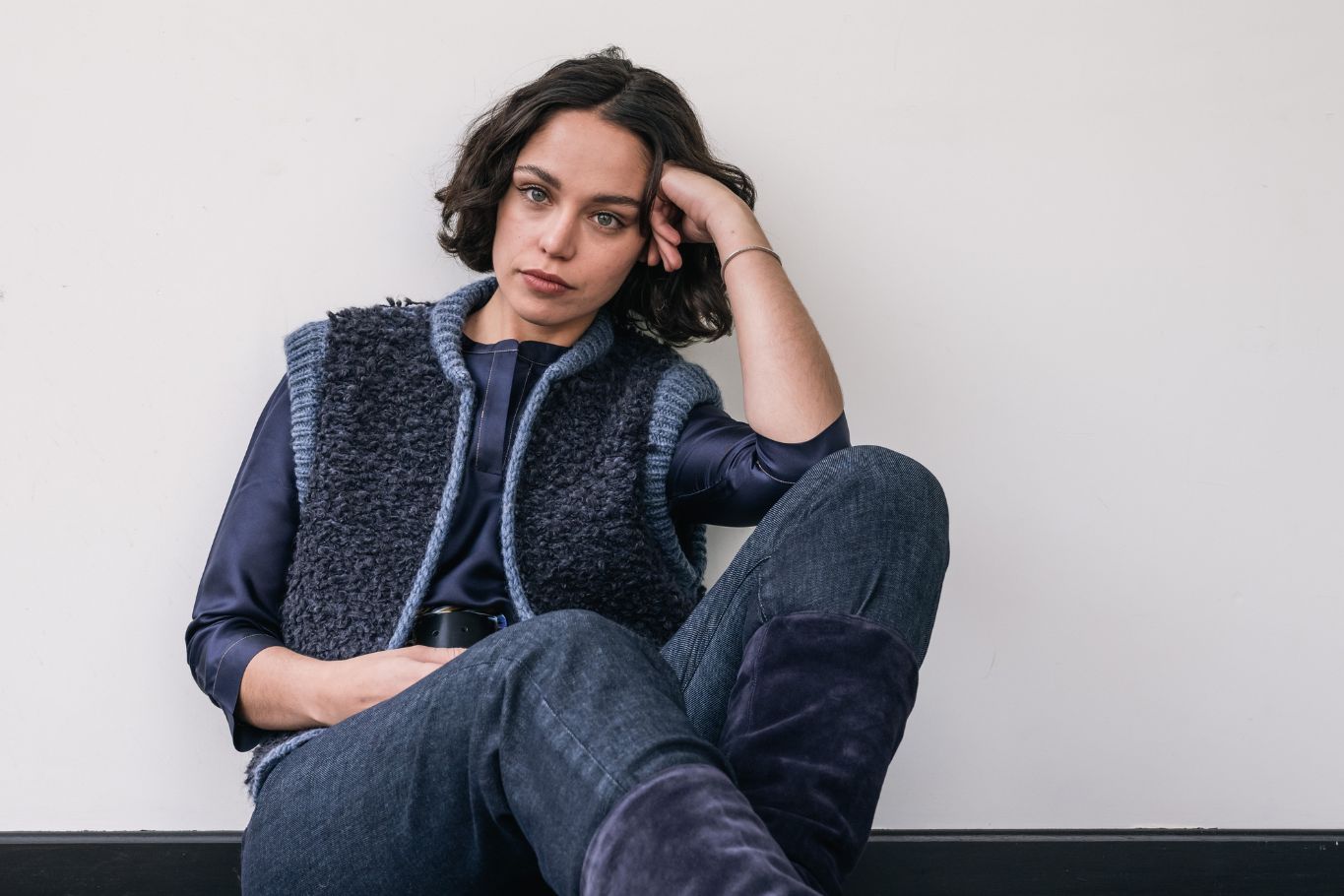 woman sitting on floor wearing wool cardigan, silk blouse and leather belt
