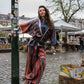 Girl leaning next to a pole, wearing a silk pants, blouse and kimono. On top of that, she wearing a bulky leather belt