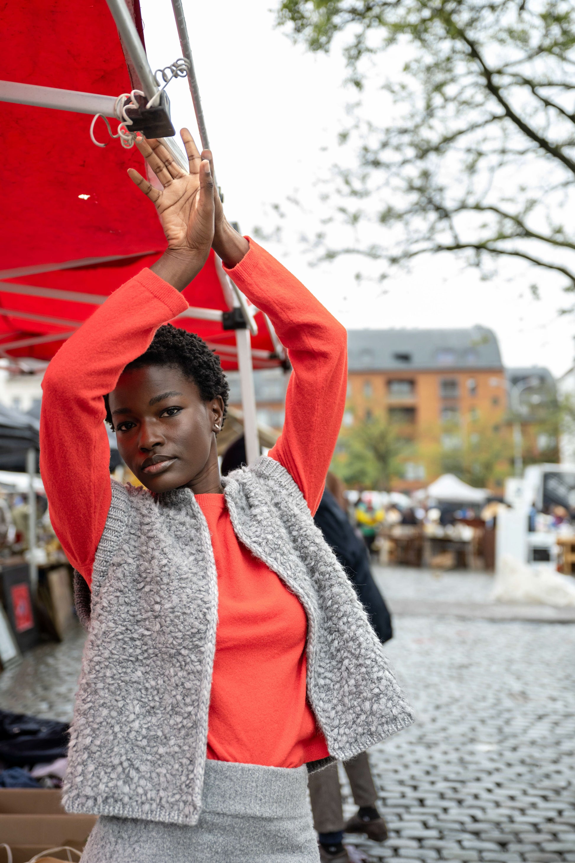 Black girl wearing a red sweater, a gray fluffy jacket, and a form-fitting gray skirt