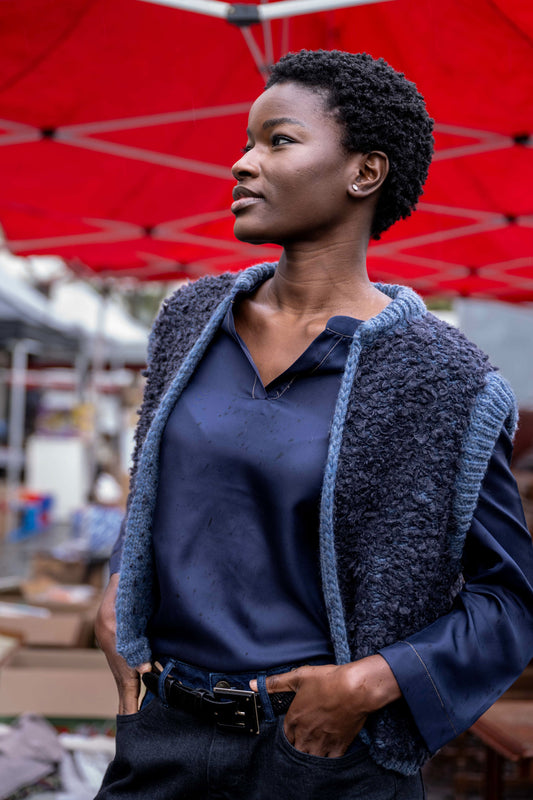 girl wearing a dark blue fluffy vest with silk blouse and leather belt