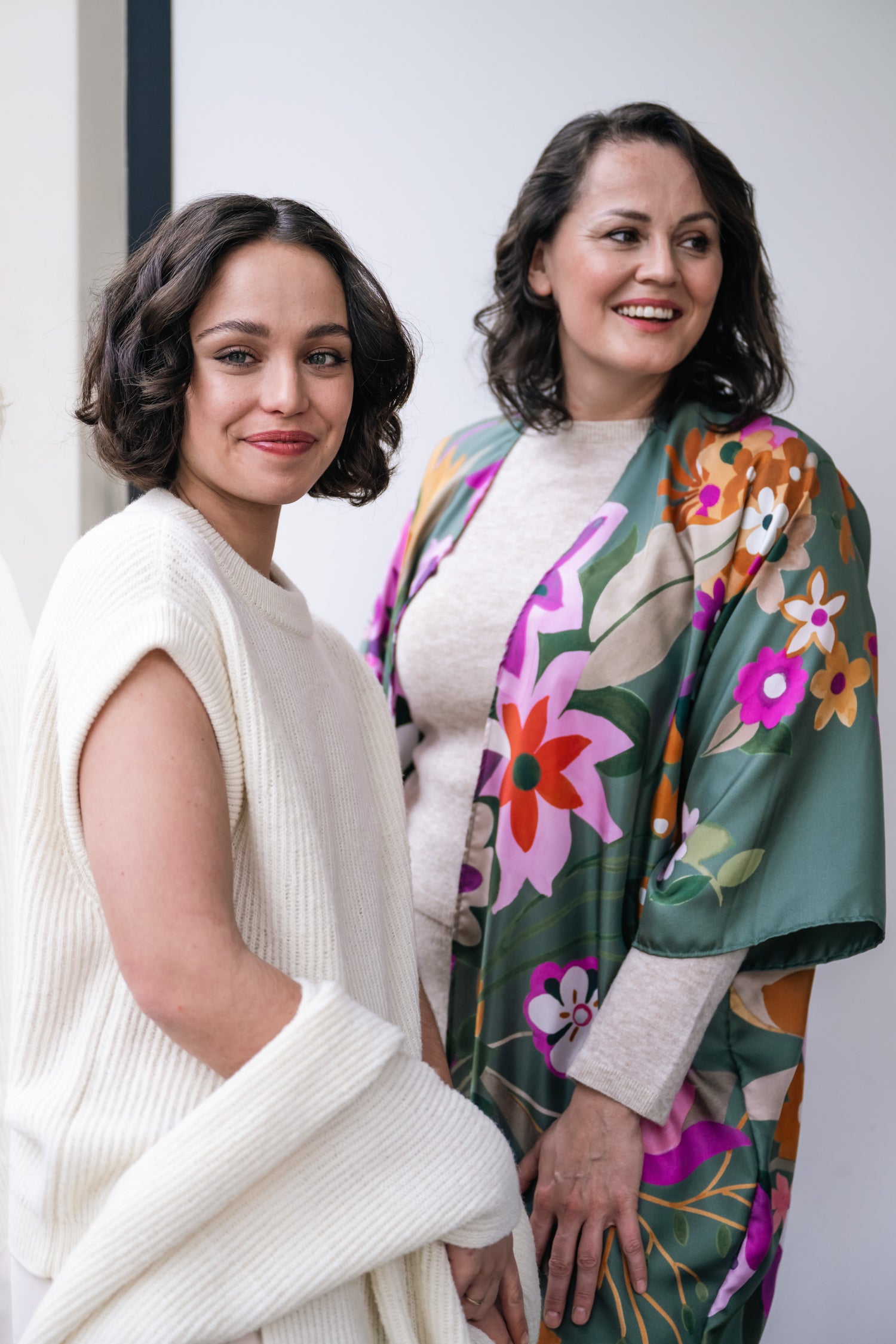 woman wearing white sweater and scarf. Other woman with green silk kimono with floral print