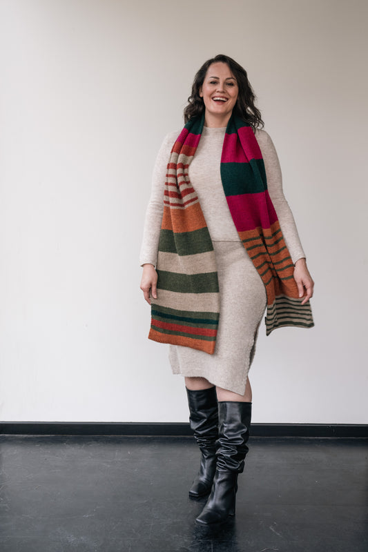 woman wearing an entire beige set - sweater and skirt. Above that, she wears a colorful scarf