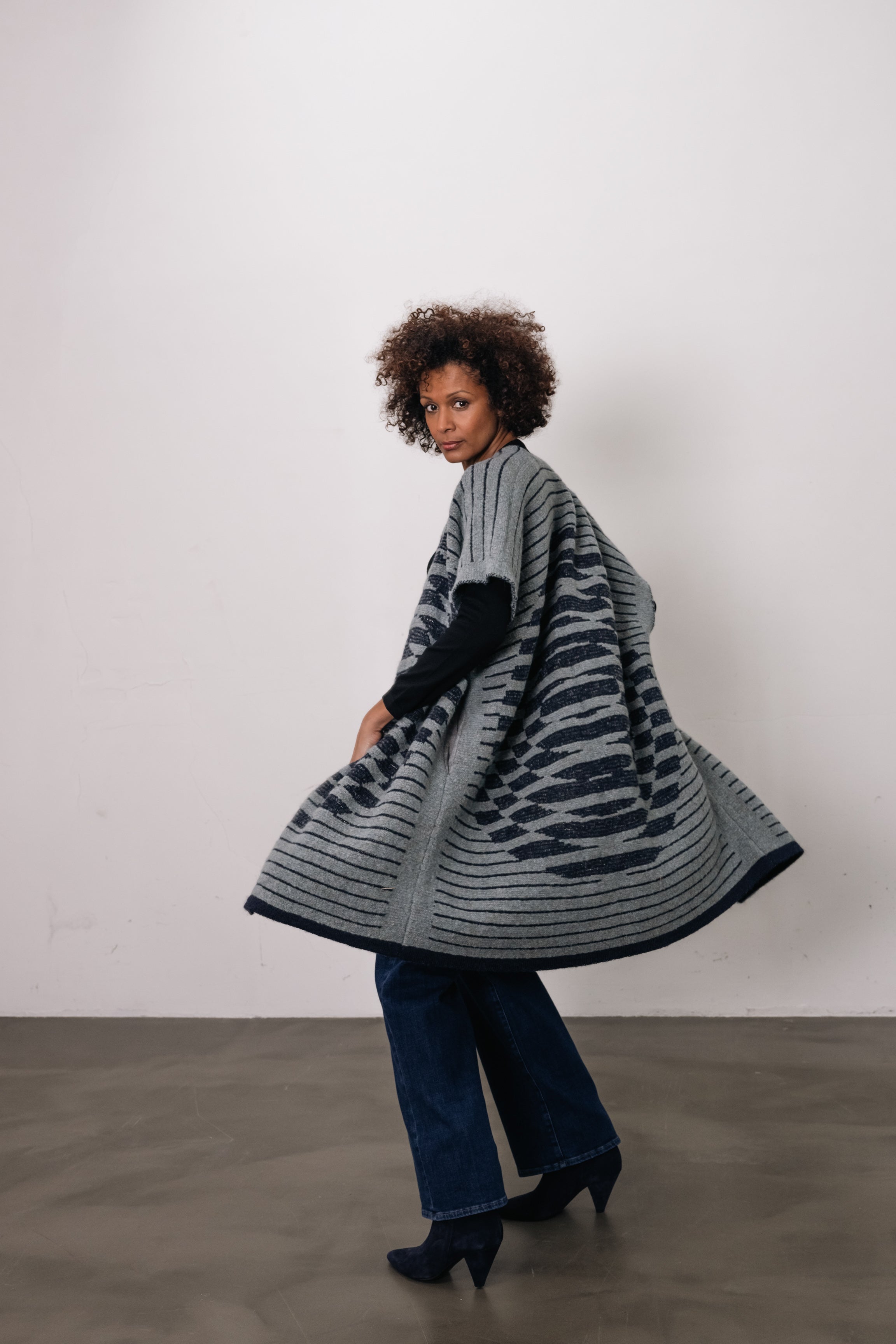 woman wears gray/blue vest with circle on back