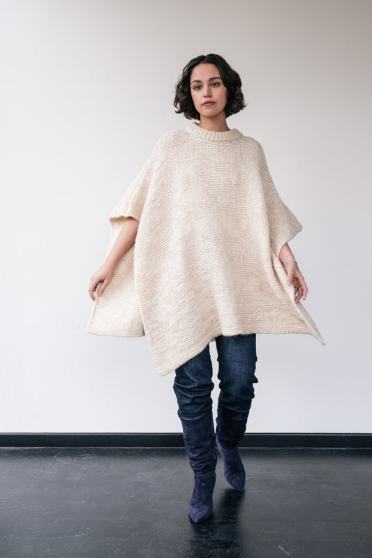 woman wears white wool poncho