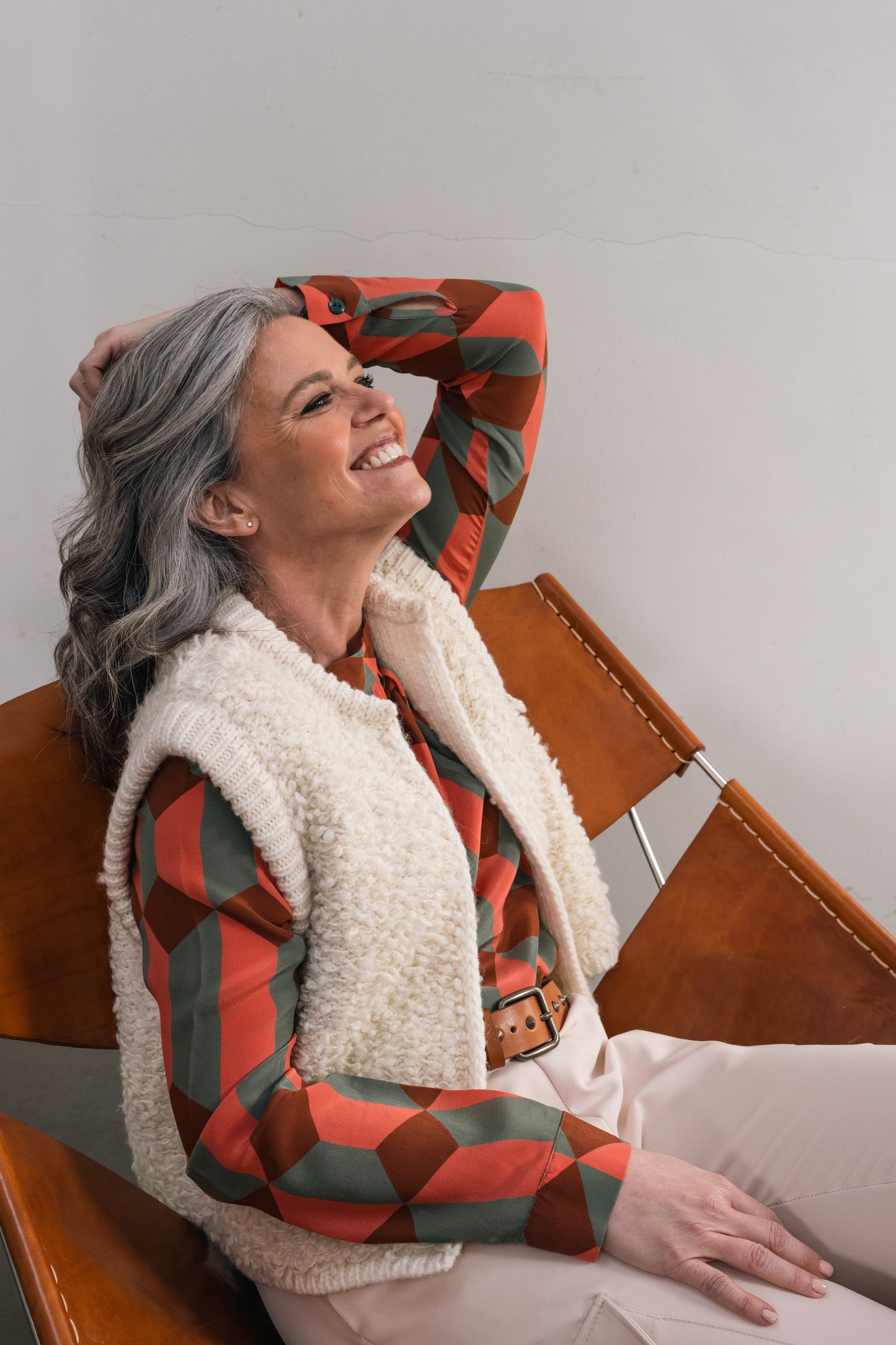 Woman in chair wearing a wool cardigan with a silk blouse and underneath a leather belt with studs