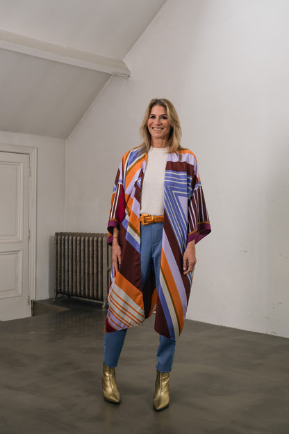 woman wears lilac-orange-bordeaux silk kimono with stripes. Underneath a wool sweater and metallic leather belt