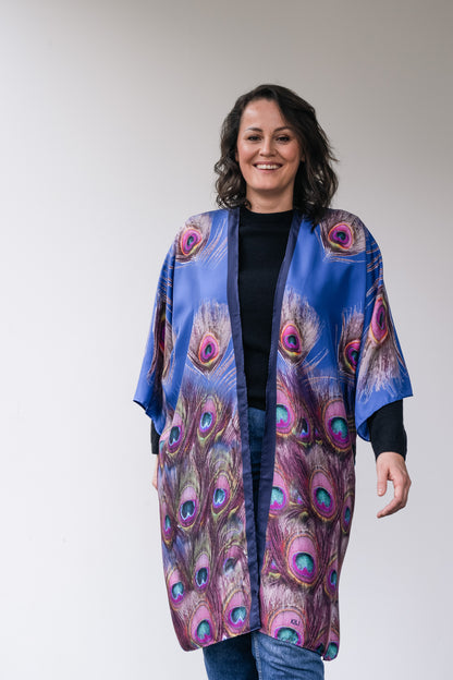 woman wears silk long kimono with blue peacock feathers