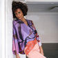 woman leaning against wall in purple silk kimono surmounted by flexible orange belt