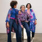 Three women wear silk kimonos with fun prints with leather belts underneath in funky colors