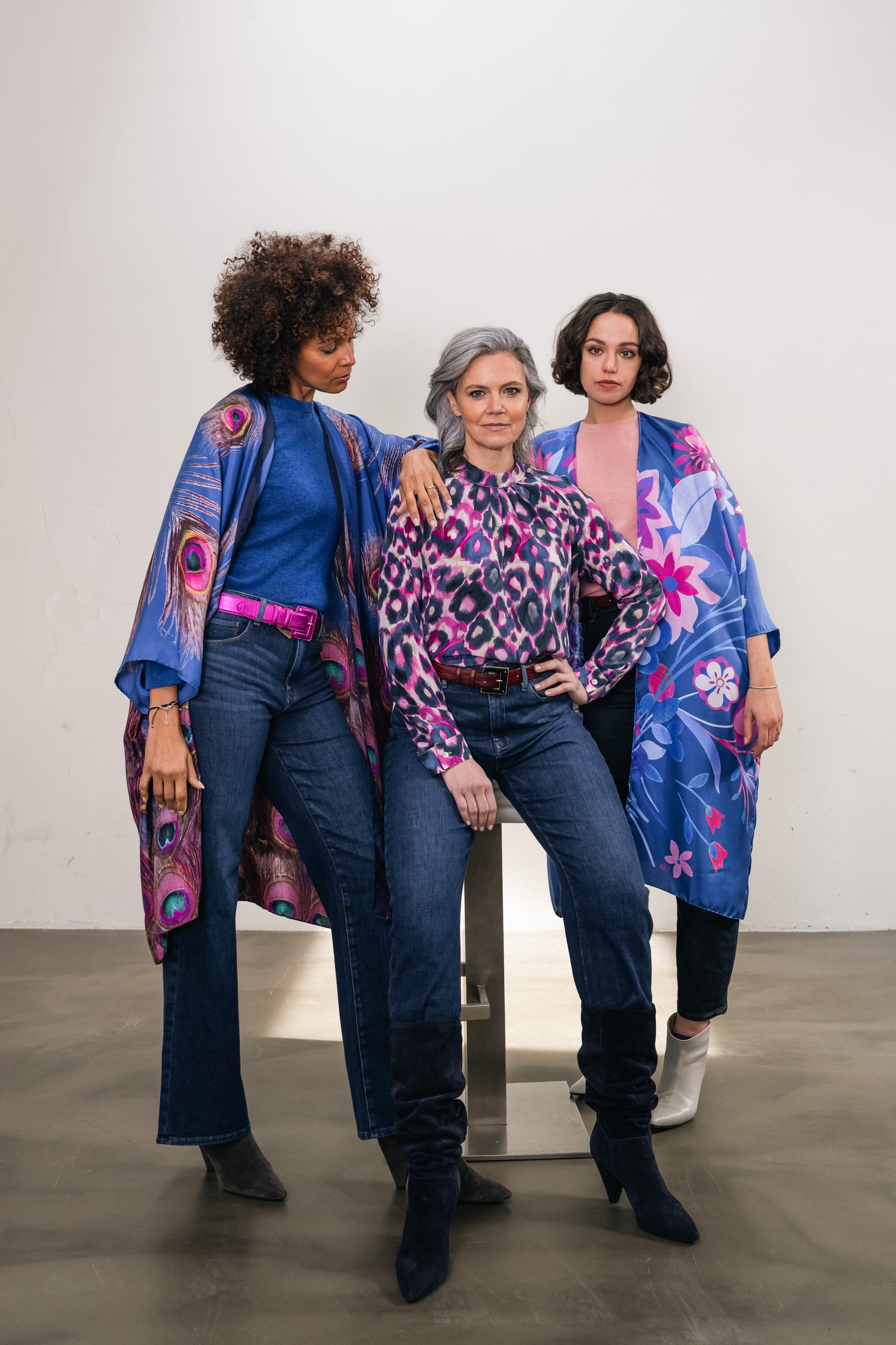Three women wear silk kimonos with fun prints with leather belts underneath in funky colors