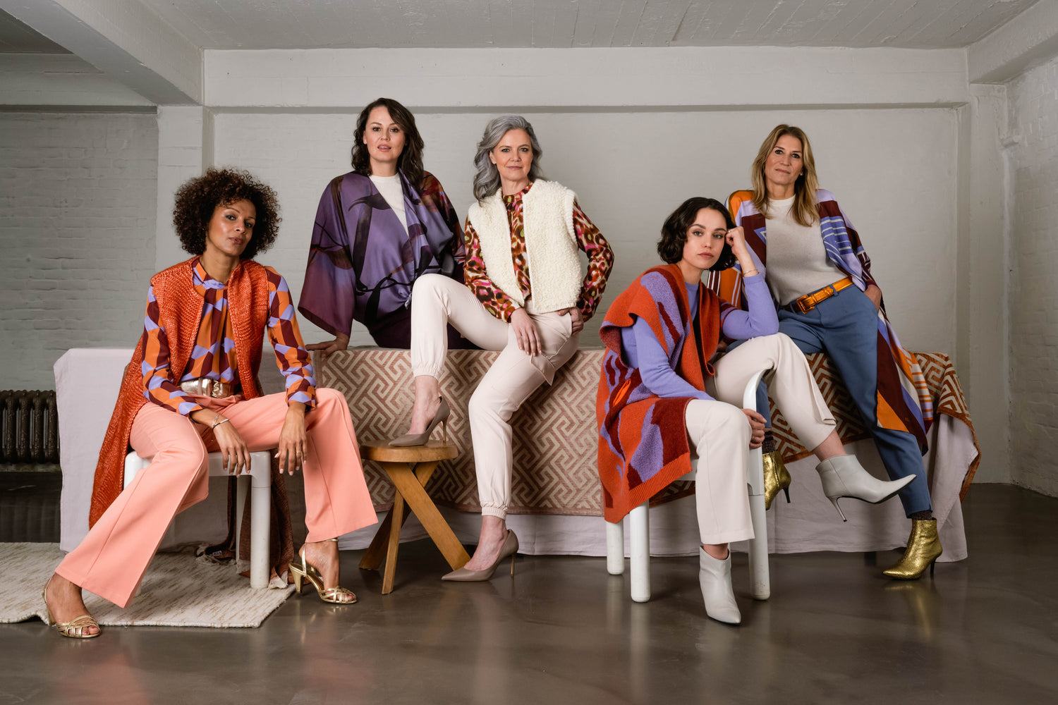 group photo of five different women. overall colors are purple and orange. Wearing different types of silk items 