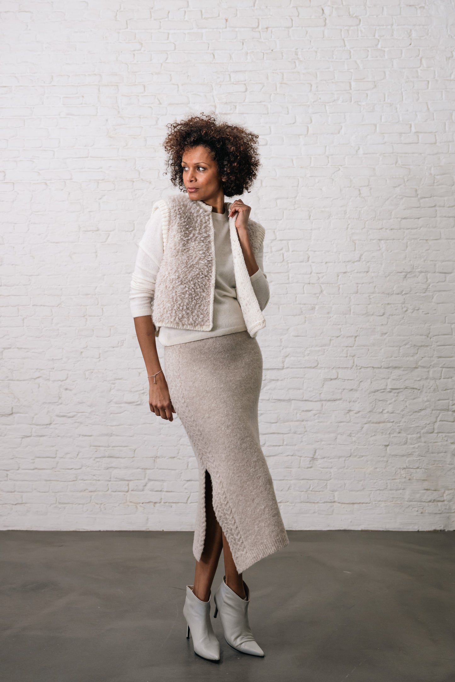 Woman wears a white wool cardigan and beige wool skirt