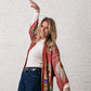 woman raising her hands in the air, wearing a cowboy belt and silk kimono in bordeaux with peacock feathers