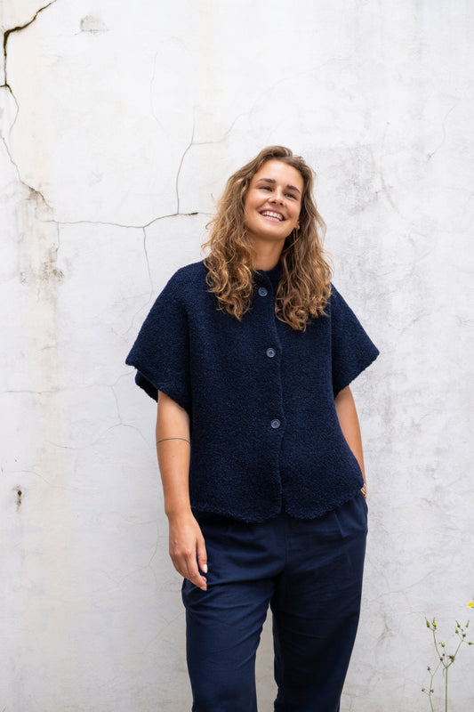 Girl wearing a dark blue cape in wool and wears a dark blue linnen pants 